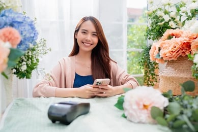 Eine Frau mit Smartphone in der Hand, informiert sich über die Möglichkeiten der Leadgenerierung in HubSpot.