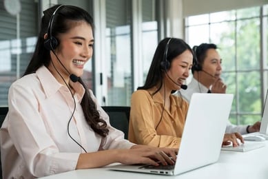 Mehrere Personen mit Headset helfen ihren Kunden mit Support via Telefon.