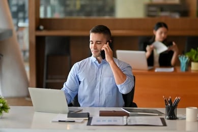 A man sits from a laptop and works on strategies to optimise ROI.