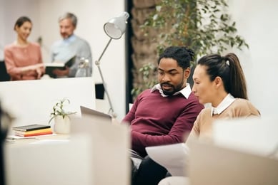 A woman shows another woman the positive effects of email marketing in a report